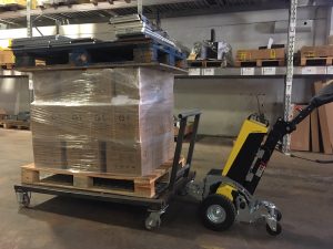 Alitrak AU LT300 Electric Tow Tug transporting heavy-duty trolleys inside a warehouse.