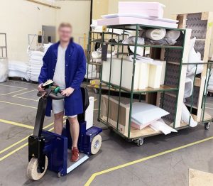 Operator using Zallys K2 Stand-On Electric Tug in manufacturing plant