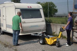 Compact electric tug transporting heavy cargo across a worksite.